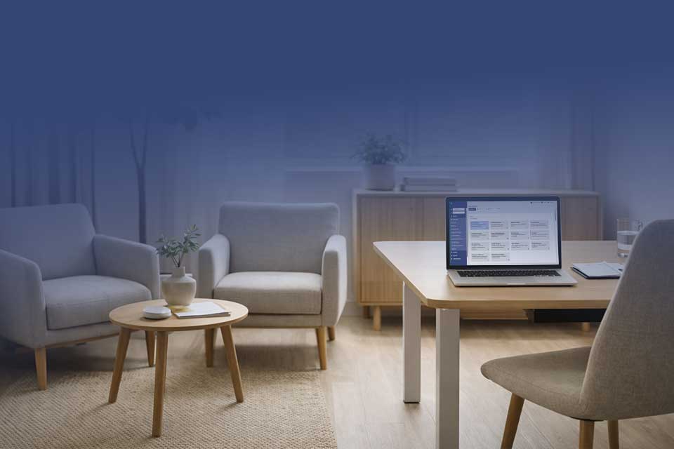 Kontorsmiljö med skrivbord och öppen laptop samt samtalsplats med två fåtöljer, symbol för strukturerat rehabiliteringsstöd för arbetsgivare.