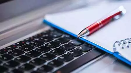 ett tangentbord med ett block och en penna på