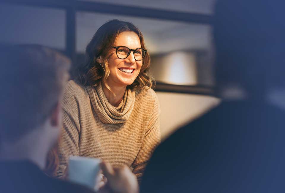 Kvinna i samtal med kollegor under en engagemangsdialog om teamutveckling på jobbet.
