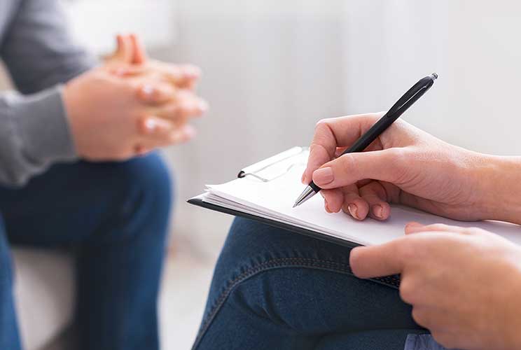 Närbild på en hand som antecknar i ett samtal om stress och psykisk ohälsa