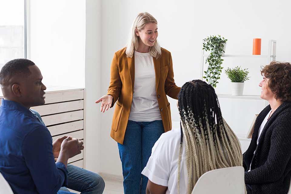 En workshopledare i samtal med en grupp medarbetare om arbetsmiljö och hälsa på arbetsplatsen.